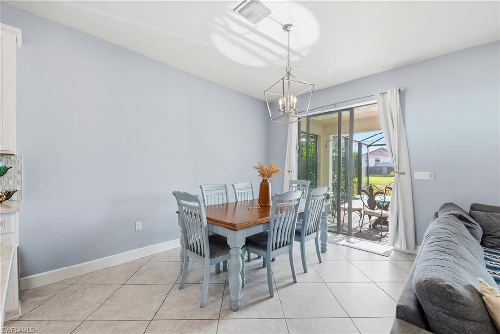 Dining area featuring a contemporary chandelier, tile flooring, and sliding glass doors opening to a screened outdoor space
