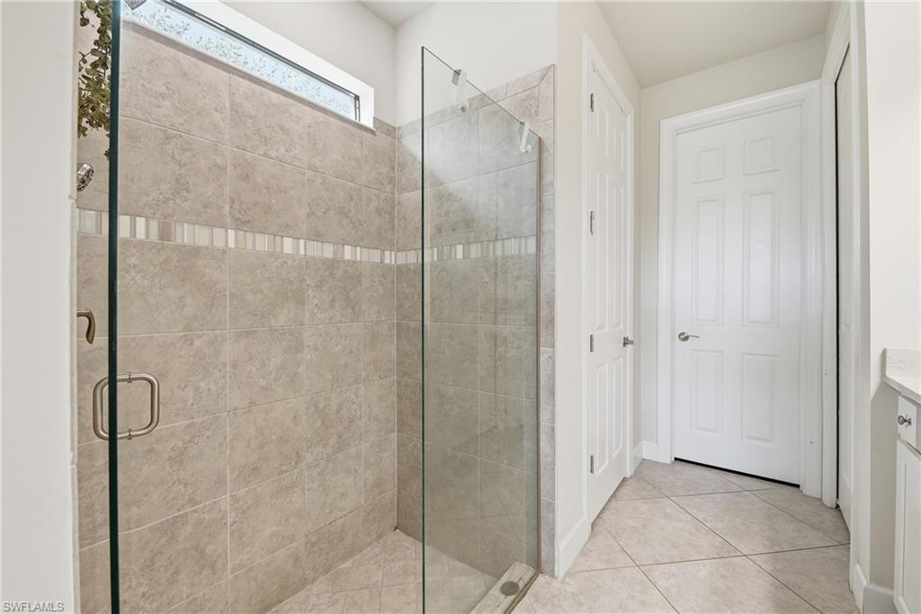 Walk-in shower with full-height tile surround, glass enclosure, and decorative tile accent band