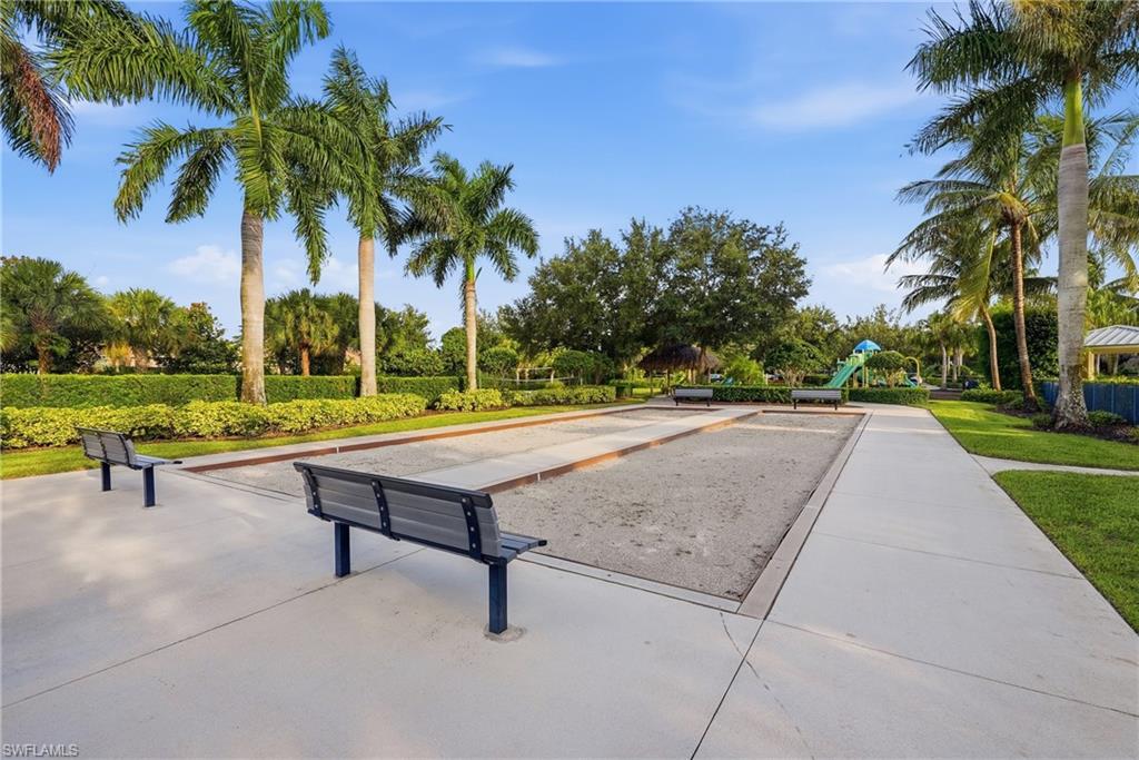 Expansive recreational grounds featuring a regulation horseshoe pit with two benches, wide concrete pathways, and mature landscaping including towering palms and established shade trees throughout the manicured lawn