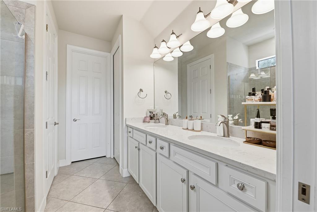 Spa-inspired primary bathroom featuring a dual-sink vanity with white cabinetry, quartz countertops, and polished nickel hardware