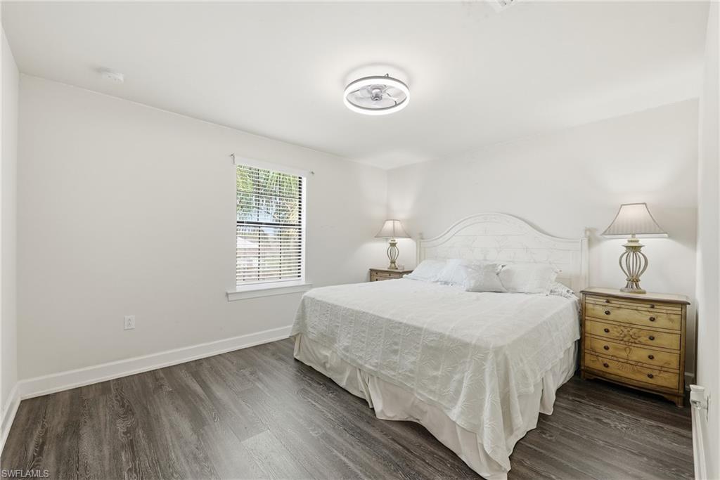 Bright interior featuring light-toned walls, wood-finish flooring, a ceiling-mounted light fixture, and a window with horizontal blinds