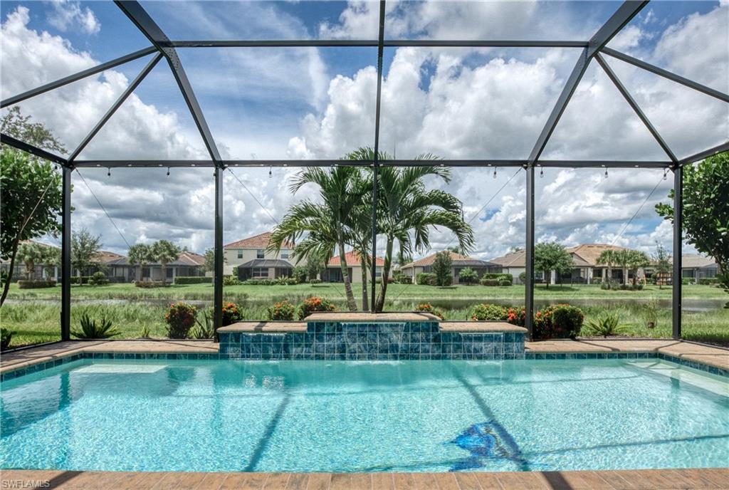 Screened-in pool area featuring a rectangular swimming pool with an integrated waterfall feature and tiled accents