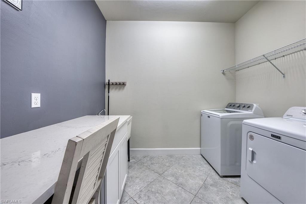 Utility room featuring a built-in countertop, undermount sink with faucet, tiled flooring, and wall-mounted shelving