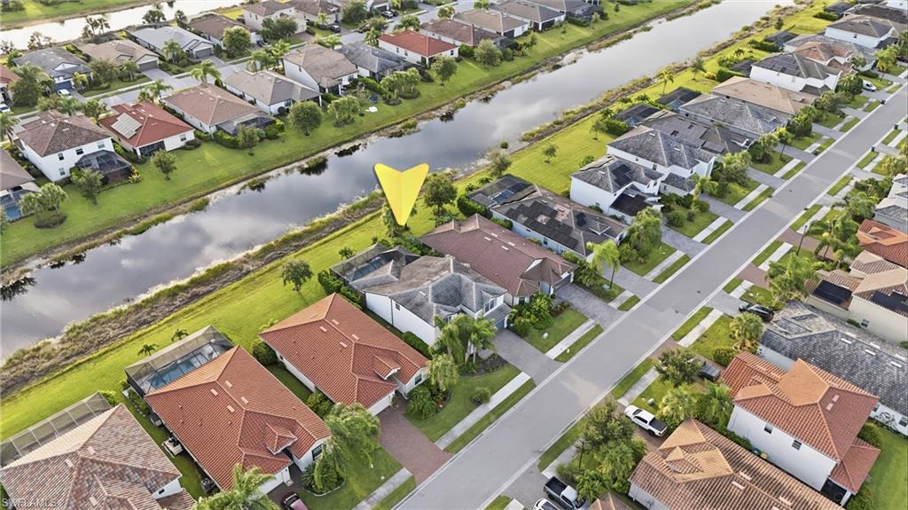 Aerial perspective of a residential neighborhood featuring a canal, paved streets, and a mix of single-story and multi-story homes