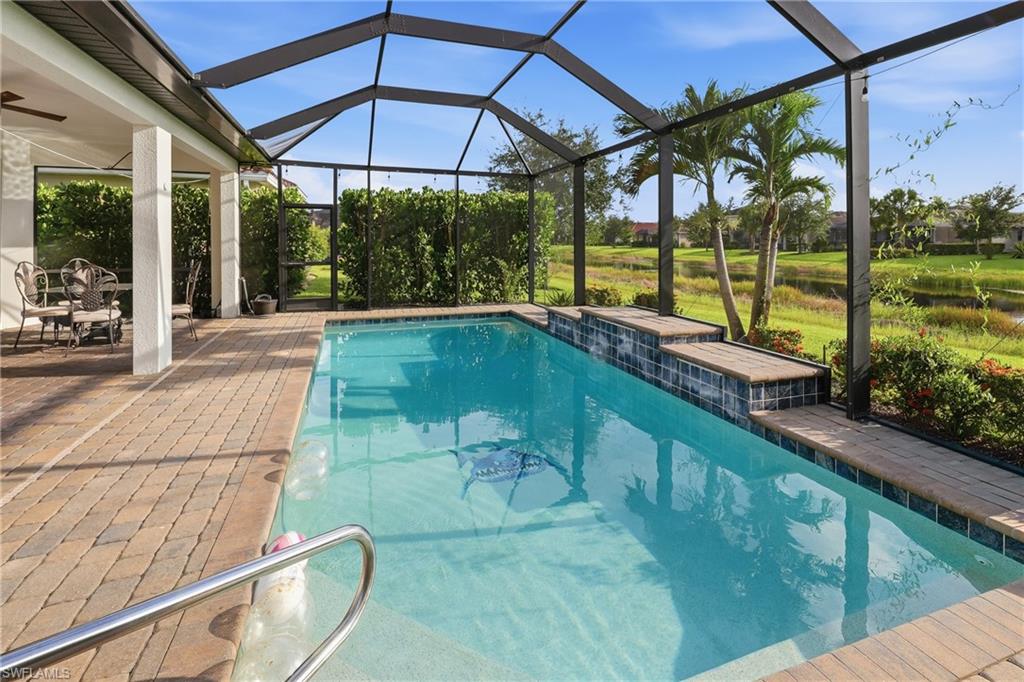 Screened-in pool deck featuring a swimming pool with steps, a paved patio, and covered lanai area