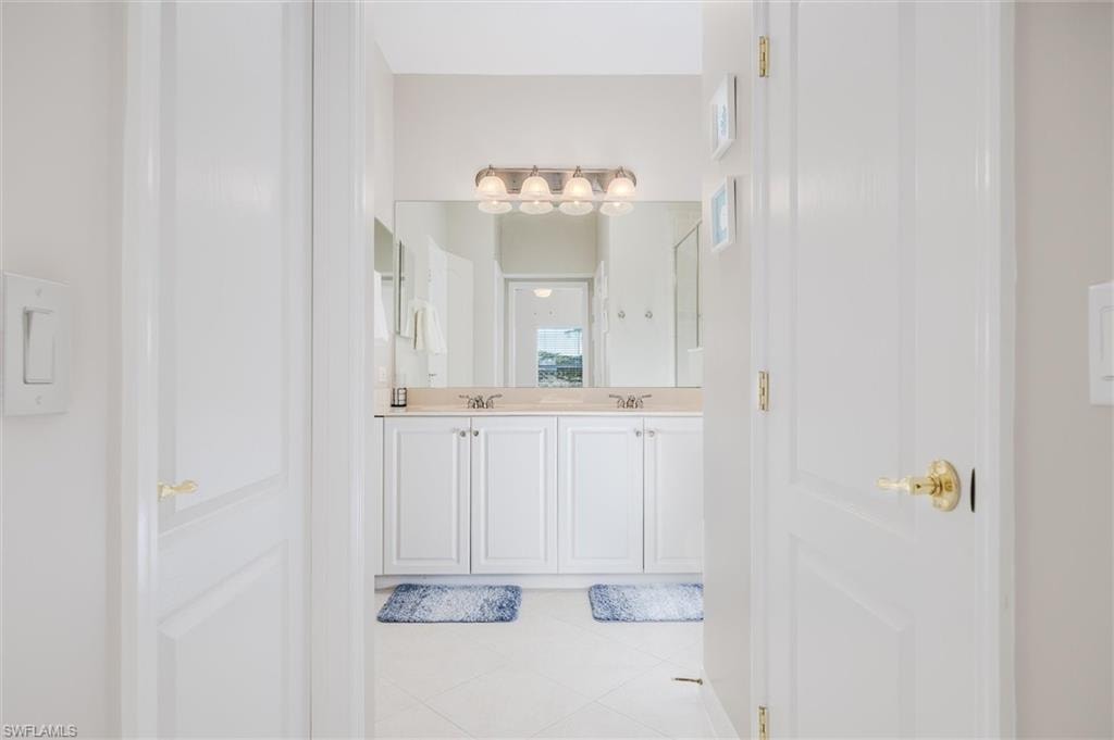 Dual sink vanity with white cabinetry, light-toned countertop, and an expansive mirror
