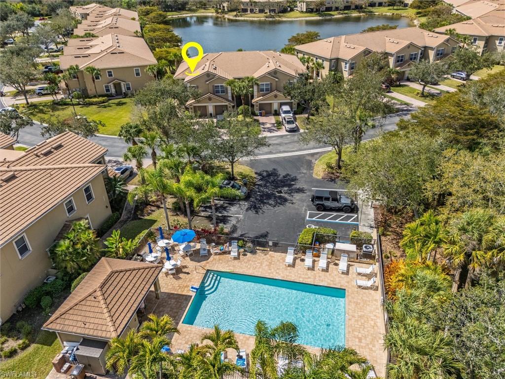 Community swimming pool with surrounding paver deck, multiple lounge chairs, and shaded outdoor seating areas