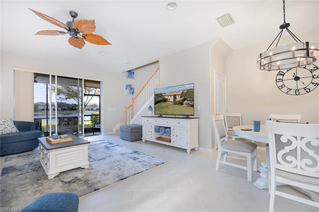 Spacious open concept living area featuring tile flooring, a staircase with wood handrails, and a contemporary dining light fixture