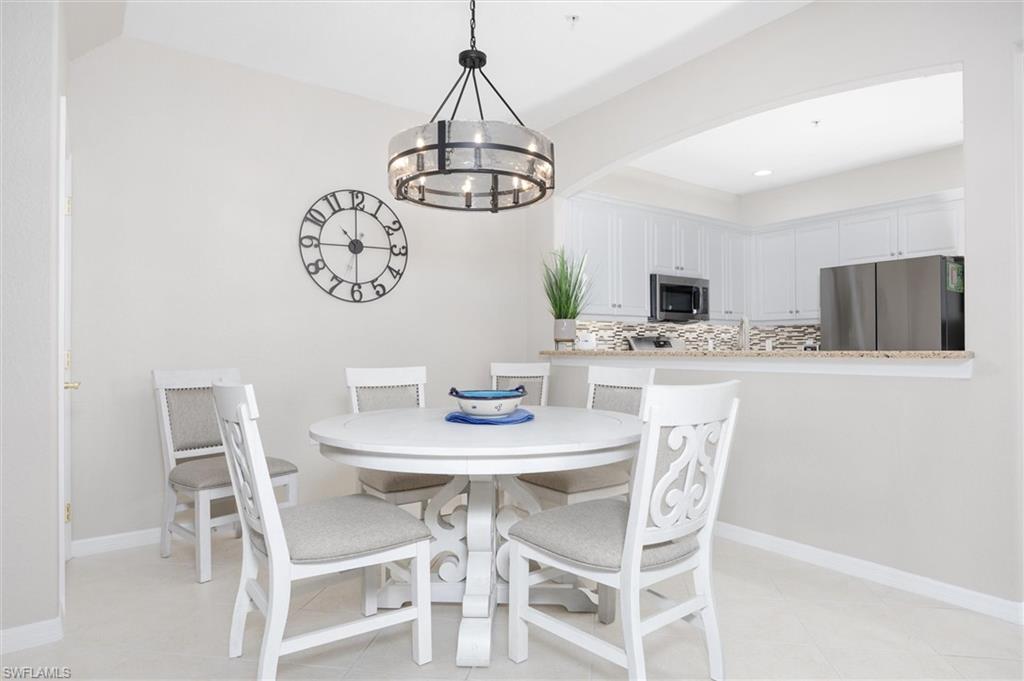 Dining area featuring a contemporary chandelier, vaulted ceiling, and light-toned flooring
