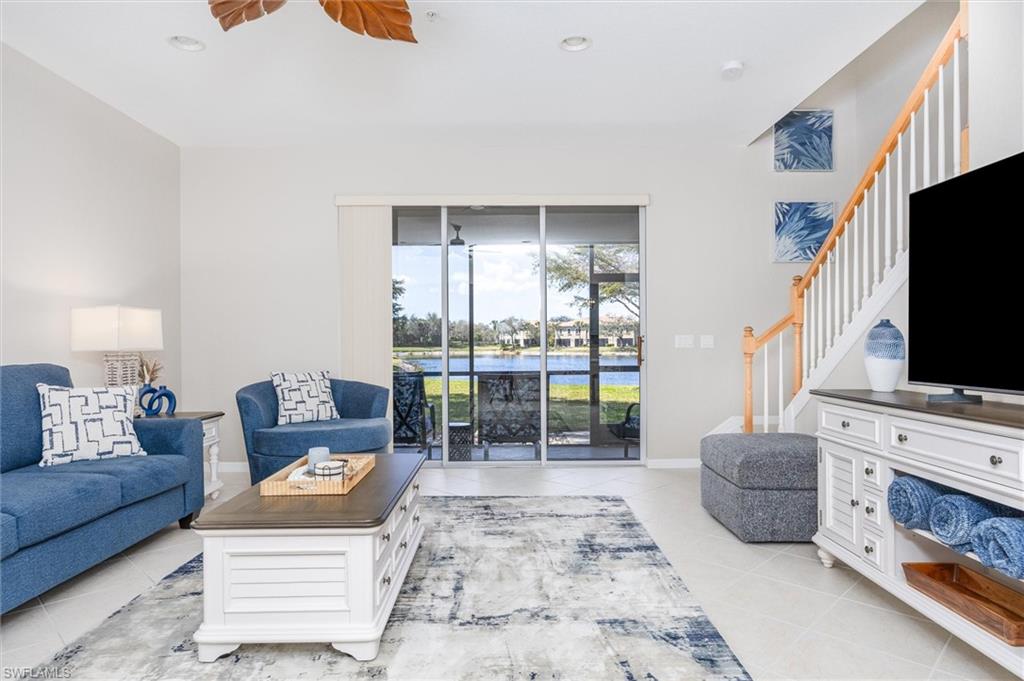 Spacious living area featuring light tile flooring and a ceiling fan with leaf-shaped blades