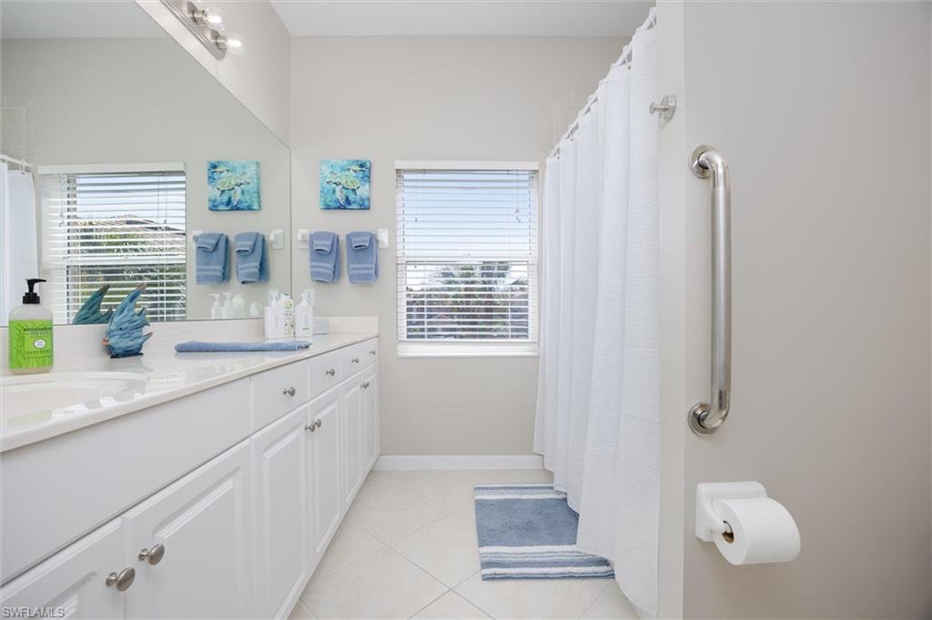 Bathroom featuring an extended vanity with dual sinks, white cabinetry, and a full-width mirror