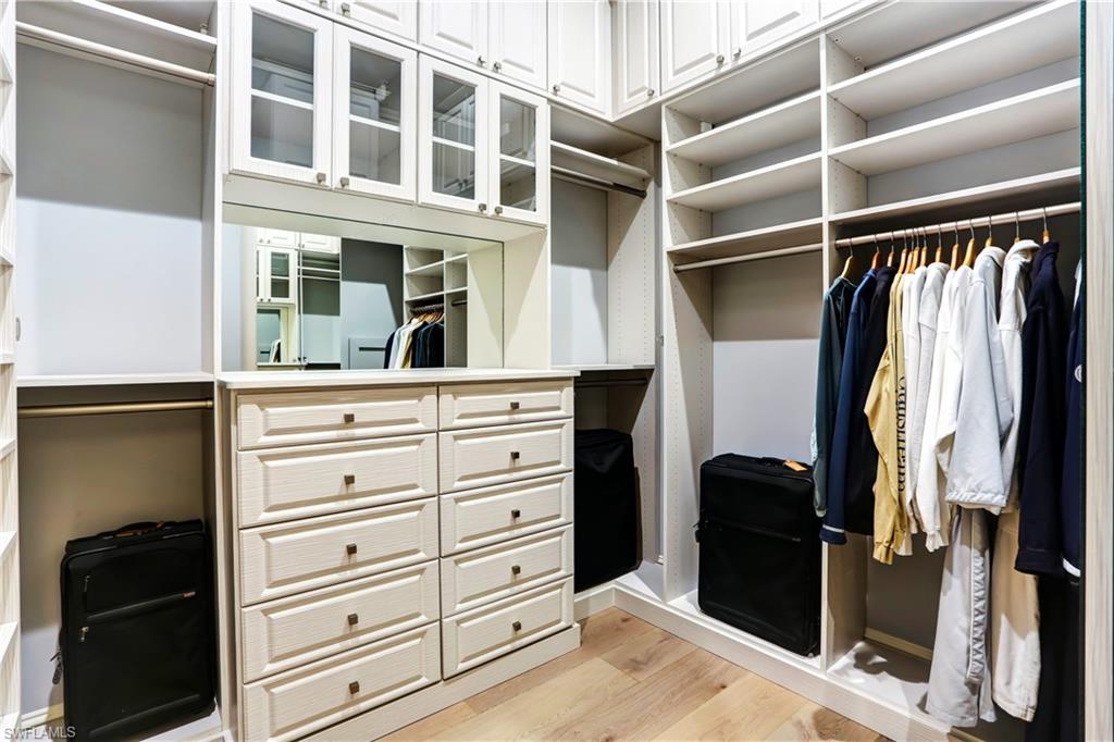 Custom closet system featuring white cabinetry and light wood-finish flooring