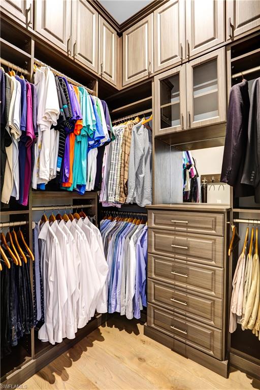 Custom closet system featuring extensive cabinetry and wood-finish flooring