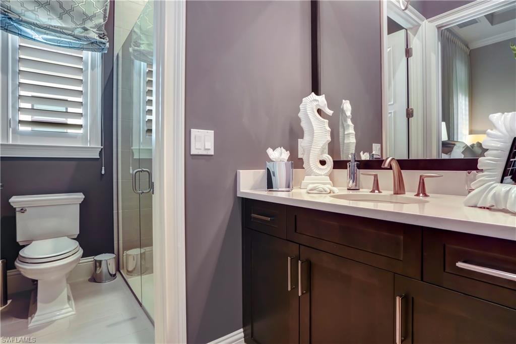 Full vanity featuring a light-toned countertop, integrated sink, and dark wood-finish cabinetry