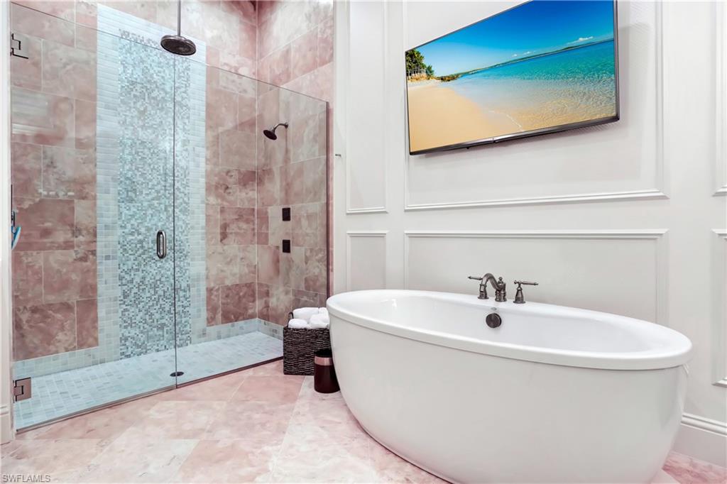 Spacious bathroom featuring a frameless glass shower enclosure with a rain shower head and a mosaic tile accent strip