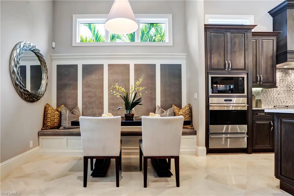 Integrated kitchen and dining area featuring a built-in banquette with upholstered seating, paneled wall detailing, and a high transom window