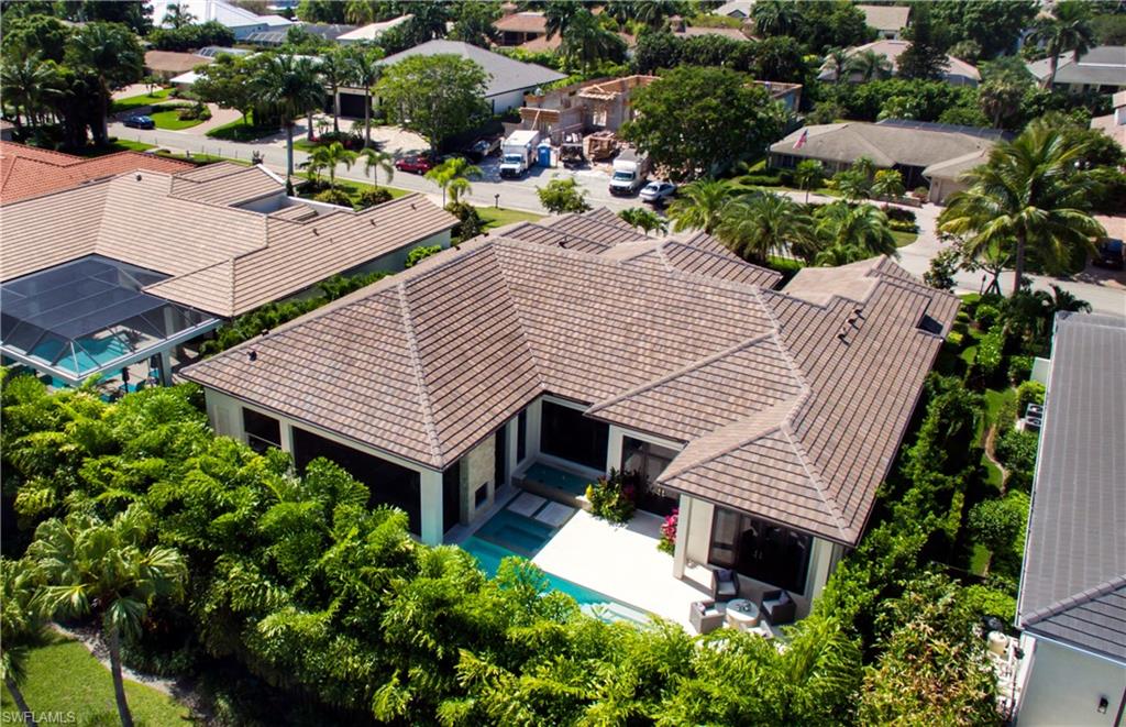 Contemporary residence featuring a tile roof, lush landscaping, and a paver patio with an outdoor seating area