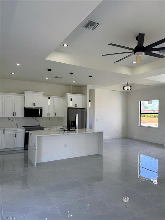 Kitchen with white cabinetry, a waterfall island, and stainless steel appliances