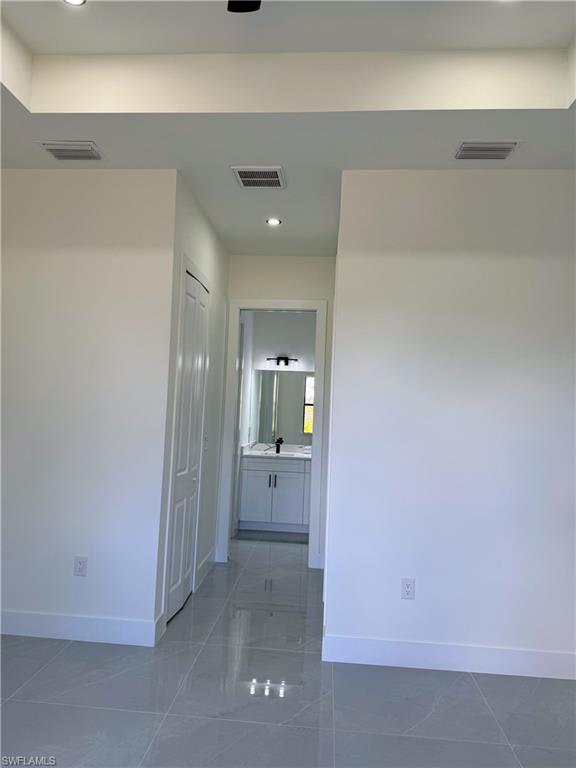 Polished tile flooring extending into a bathroom with a white vanity and wall-mounted mirror