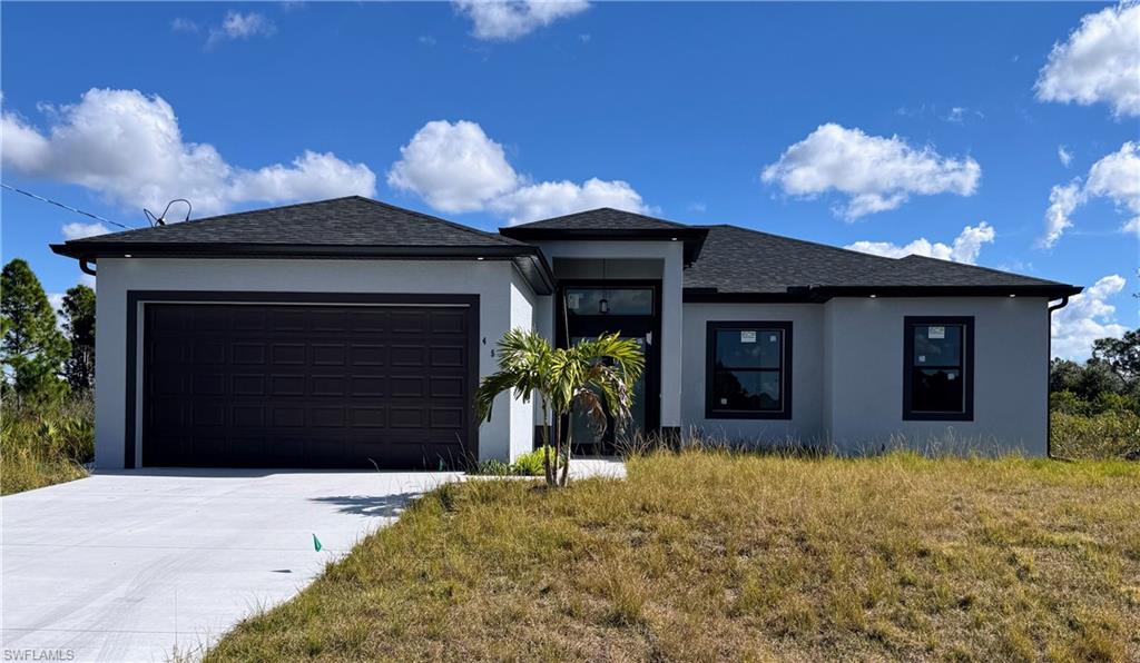 Contemporary exterior featuring a light gray stucco finish, dark asphalt shingle roof, black framed windows, and an attached two-car garage with a dark paneled door