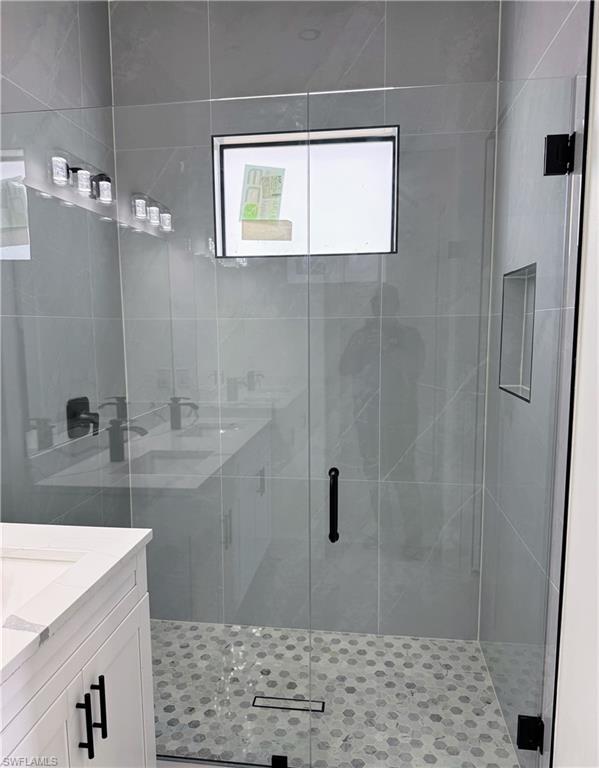Modern shower enclosure featuring a clear glass door, hexagon-patterned floor tiling, and a linear drain
