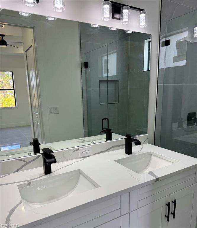 Dual vanity with white cabinetry, quartz countertop, and black fixtures