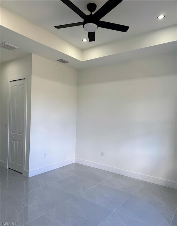 Tray ceiling with recessed lighting and a contemporary black ceiling fan