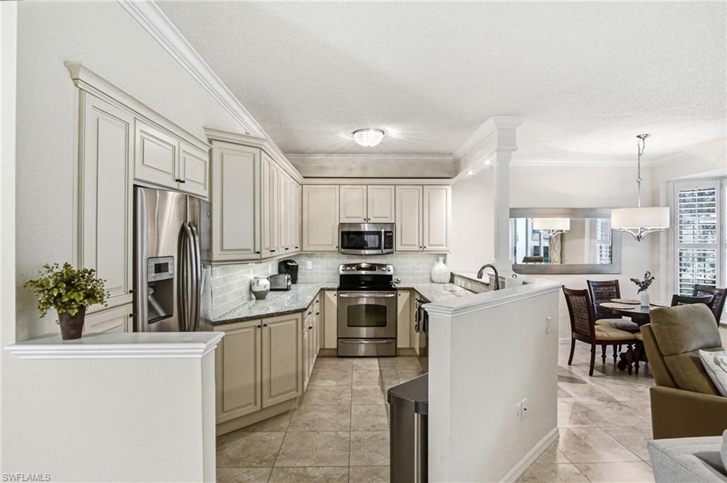Kitchen featuring light-toned cabinetry, stainless steel appliances, granite countertops, subway tile backsplash, and tile flooring