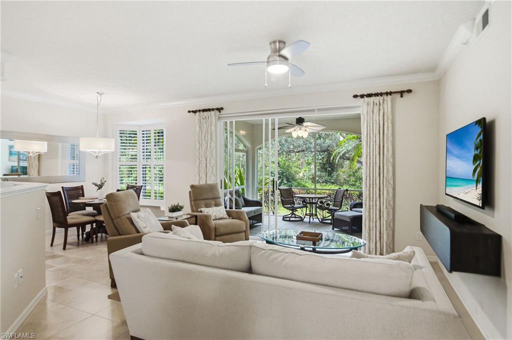 Open-concept living area featuring a curved sectional sofa, neutral tile flooring, and recessed ceiling lighting