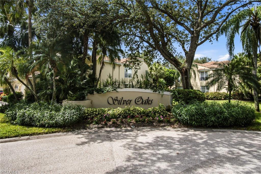 Entrance sign for "Silver Oaks" with decorative script, surrounded by mature landscaping and tropical foliage