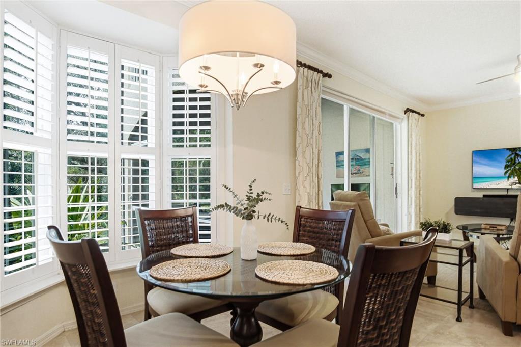 Elegant dining area anchored by a round pedestal table and upholstered chairs, illuminated by a cylindrical drum pendant fixture