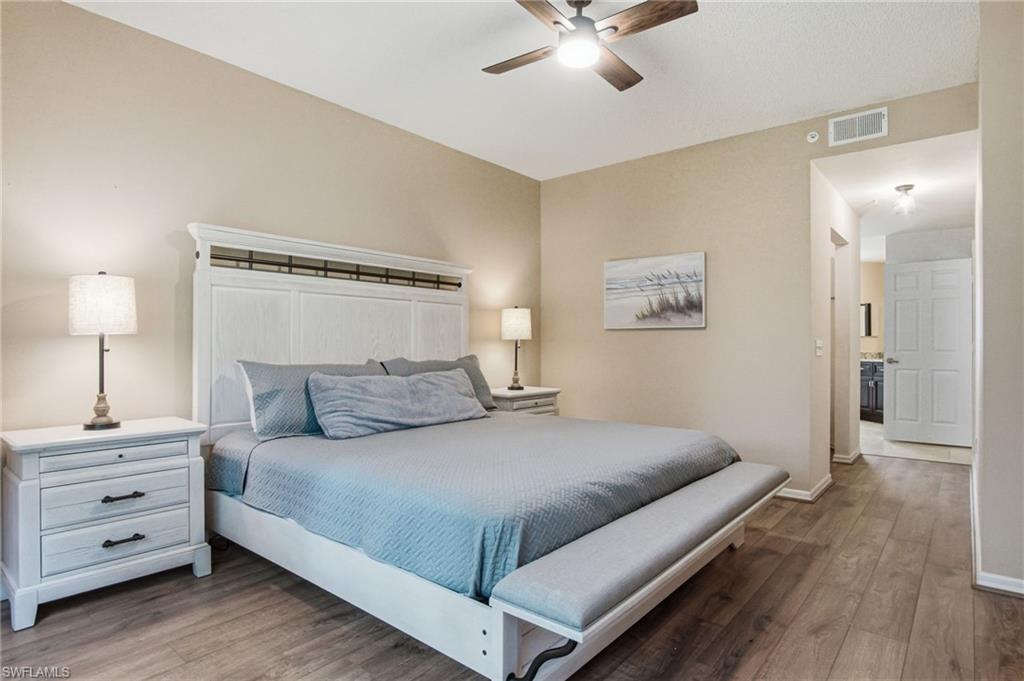 Spacious bedroom featuring wood-finish flooring, a ceiling fan with integrated lighting, and neutral wall tones