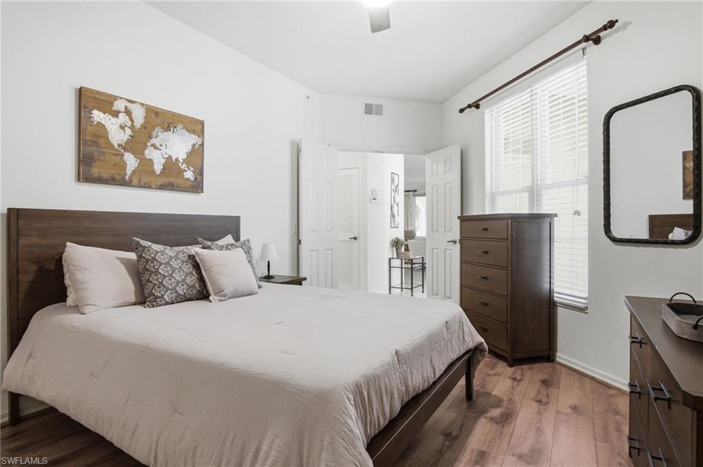Spacious primary bedroom featuring a wood-finish platform bed with upholstered headboard, neutral bedding, and coordinating accent pillows