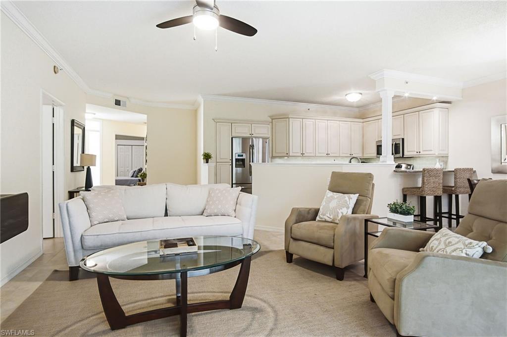 Expansive open-concept living area featuring a ceiling fan, crown molding, and light-toned walls