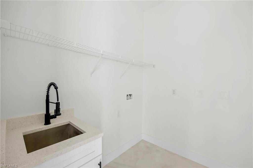 Utility room featuring a built-in sink with a black pull-down faucet, light-toned countertop, and white cabinetry