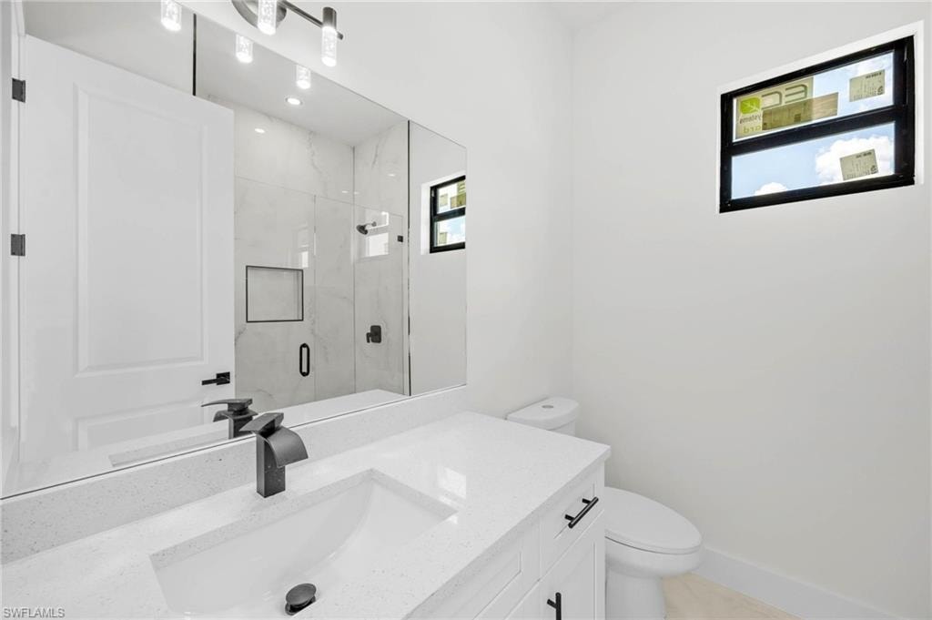 Modern bathroom featuring a single vanity with a white countertop and integrated sink, matte black faucet, and white cabinetry