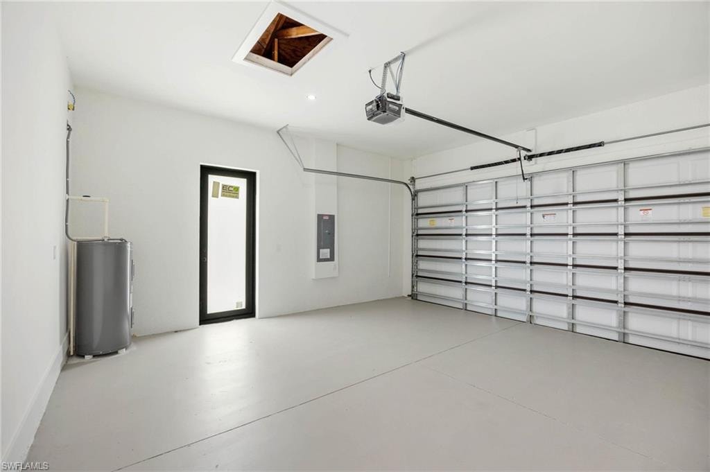 Spacious garage featuring a painted concrete floor, insulated garage door, water heater, and a side entry door