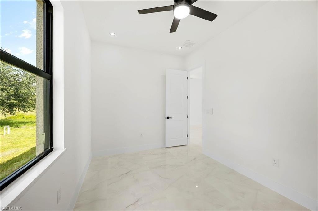Interior room featuring light-toned tile flooring, a window with black trim, and a ceiling fan with integrated lighting