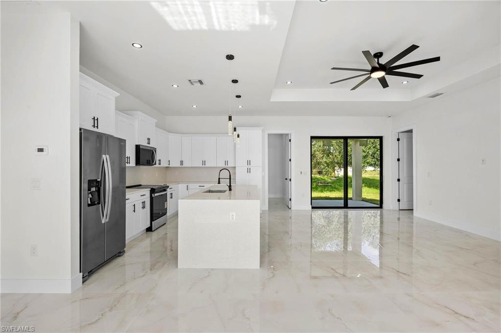 Open concept living area featuring a modern kitchen with white cabinetry and stainless steel appliances