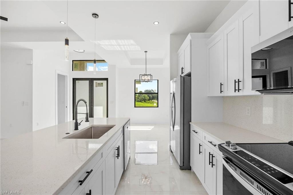 Modern kitchen featuring white shaker cabinetry with black hardware, white countertops, and a large center island with an undermount sink and gooseneck faucet
