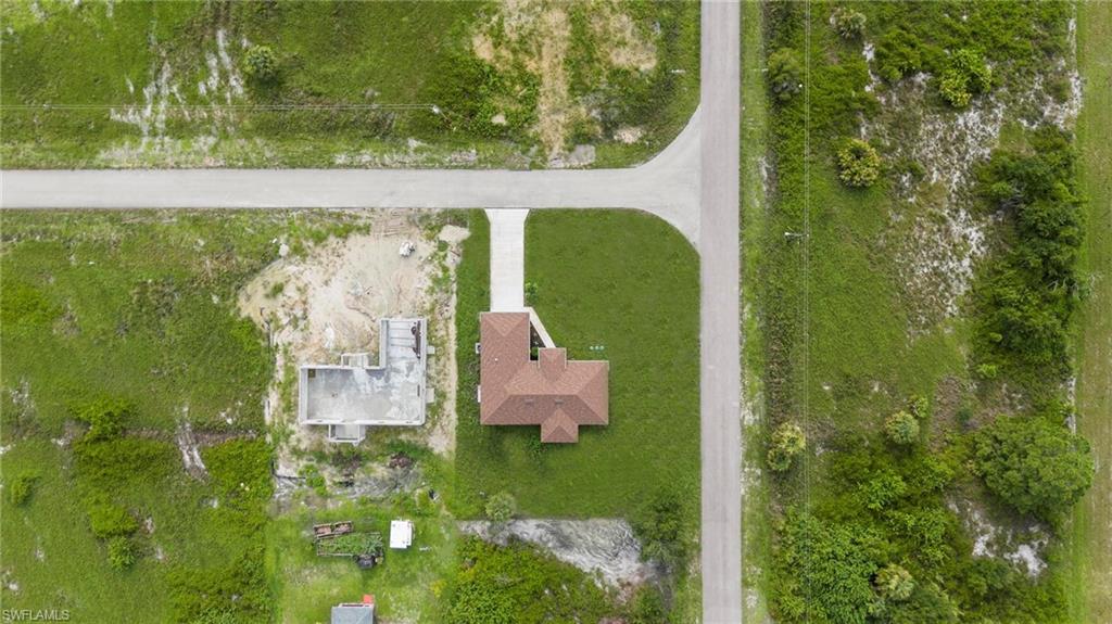 Aerial perspective highlighting a single-story residence with a brown shingle roof and an attached concrete driveway