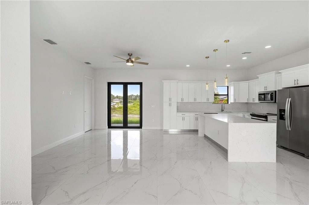 Open-concept living space featuring a modern kitchen with a large island, white cabinetry, and stainless steel appliances