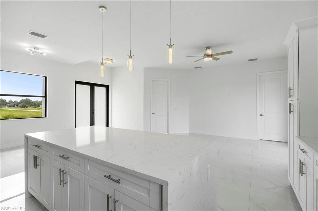 Spacious kitchen island with a light-toned countertop, complemented by white cabinetry and contemporary pendant lighting