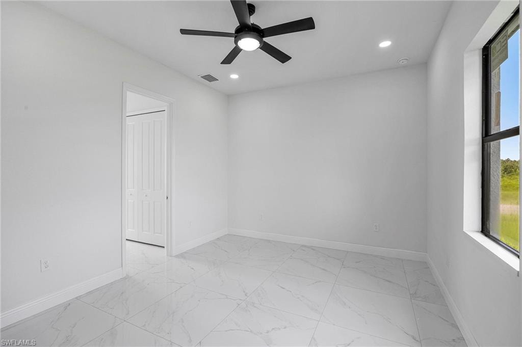 Bright interior space featuring large format tile flooring and a black ceiling fan with integrated lighting
