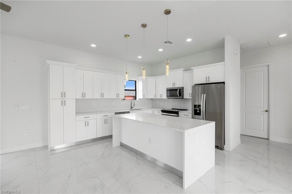 Contemporary kitchen featuring white cabinetry, a large center island with a waterfall countertop, stainless steel appliances, recessed lighting, and large format tiled flooring
