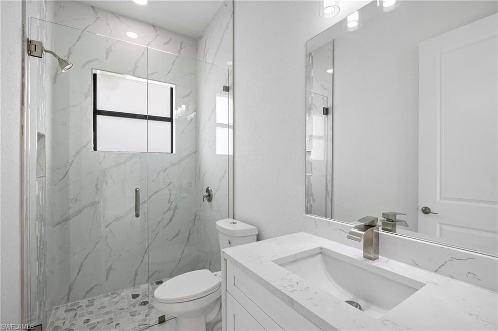 Bathroom featuring a clear glass shower enclosure with marbled tile walls and a mosaic tile floor
