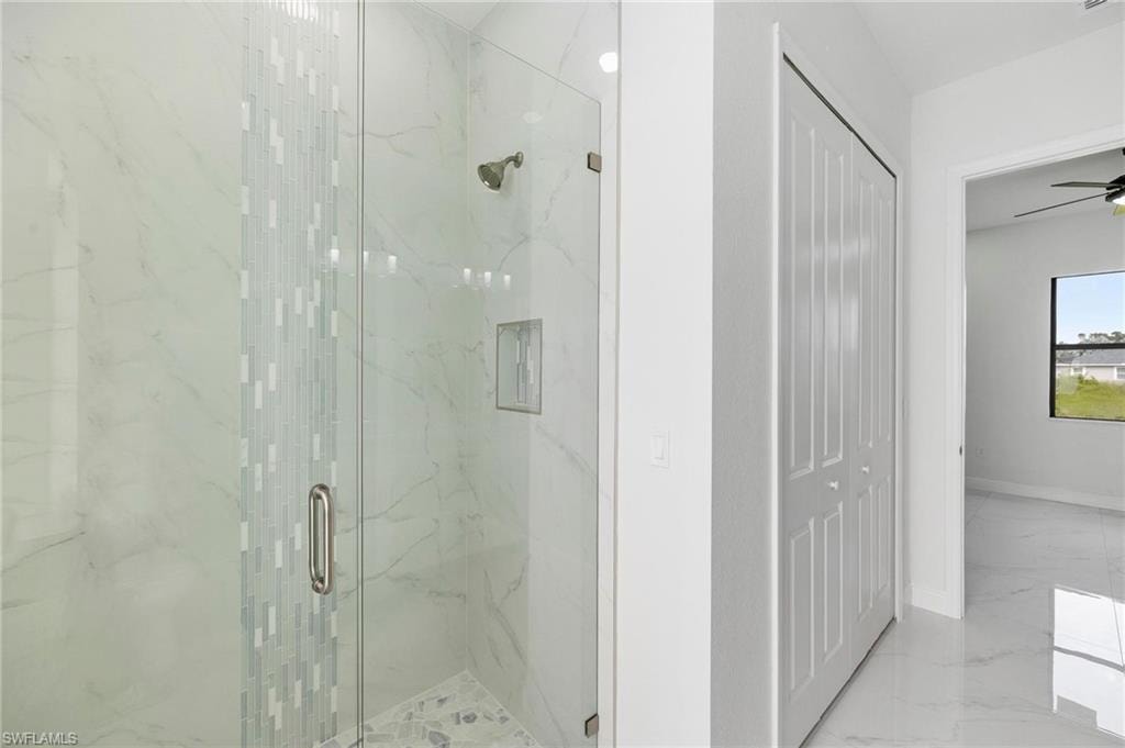 Glass-enclosed shower with white marble-style tile, decorative accent tiling, and a built-in shower niche