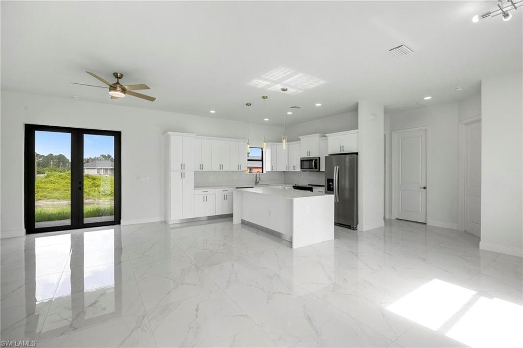 Open-concept living area featuring large format marble-look tile flooring, a modern ceiling fan, and double glass doors