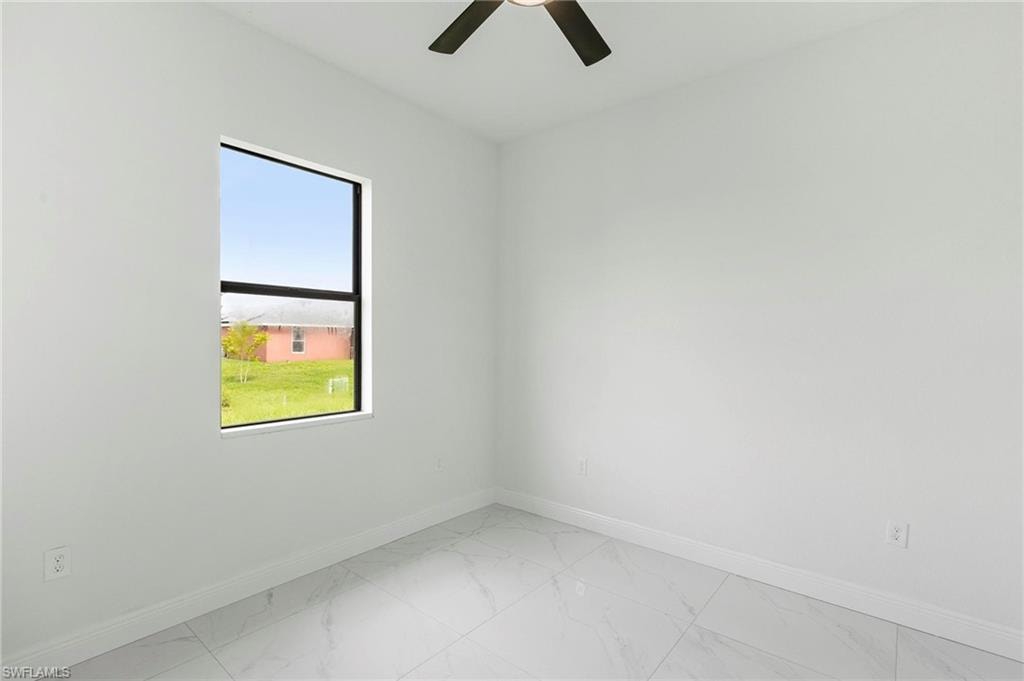 Bright room featuring a large rectangular window, white walls, white baseboards, and light-toned tile flooring
