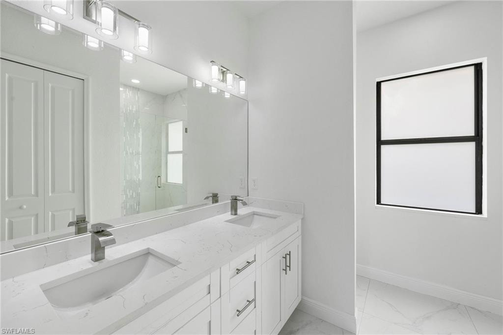 Double vanity featuring integrated sinks, chrome faucets, and a full-width mirror with overhead light fixtures
